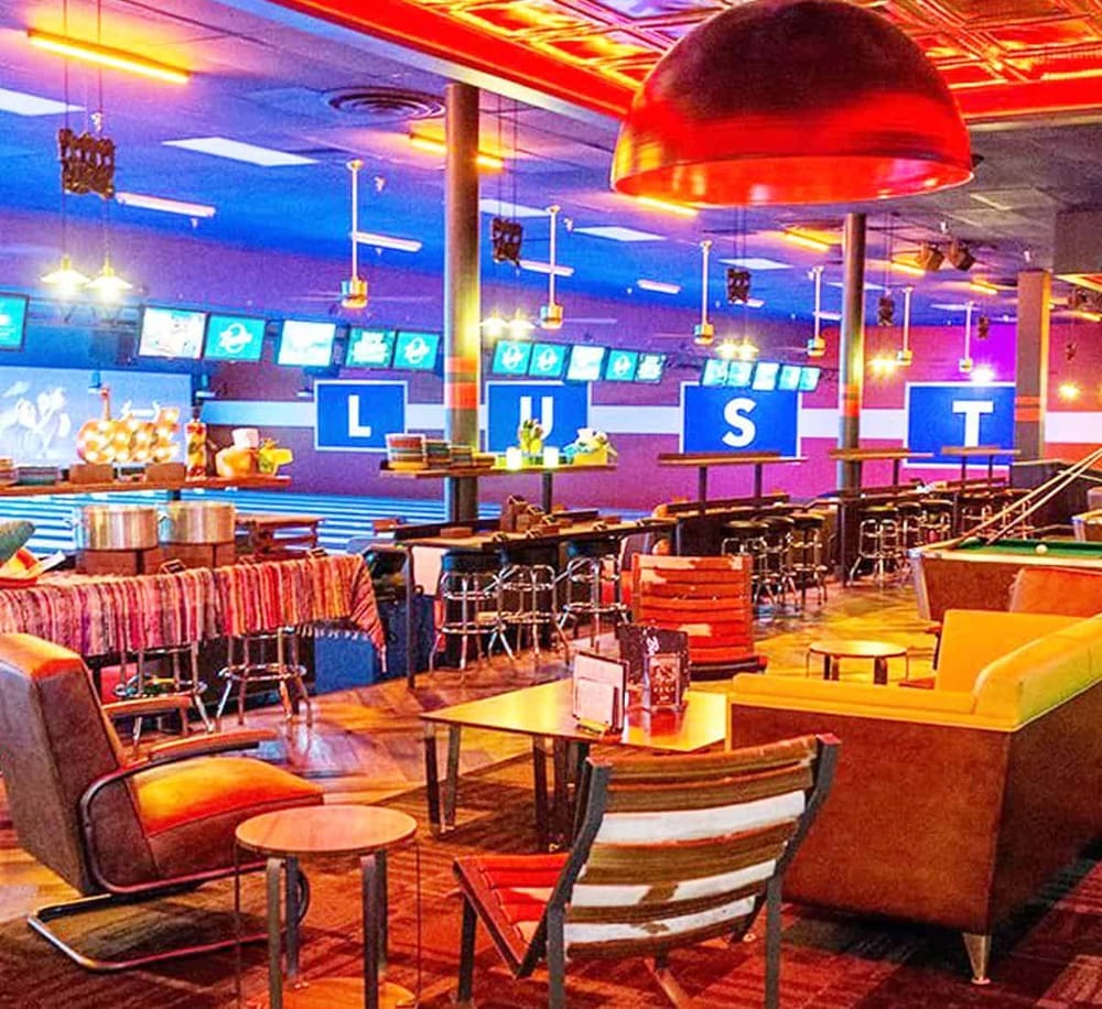 Bright sports bar interior with colorful lighting and multiple screens displaying live games.