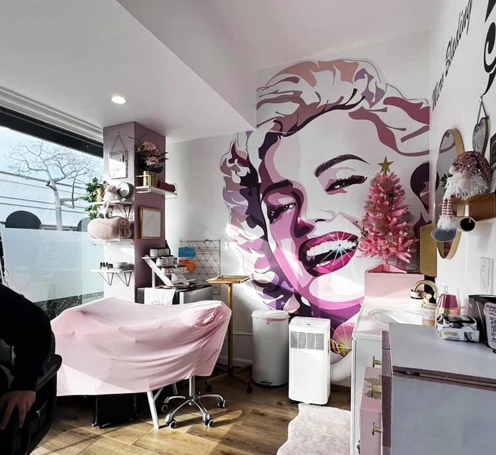 Vibrant Marilyn Monroe wall art decor at QuestForDirections, a trendy beauty salon with festive pink Christmas tree and modern interior.