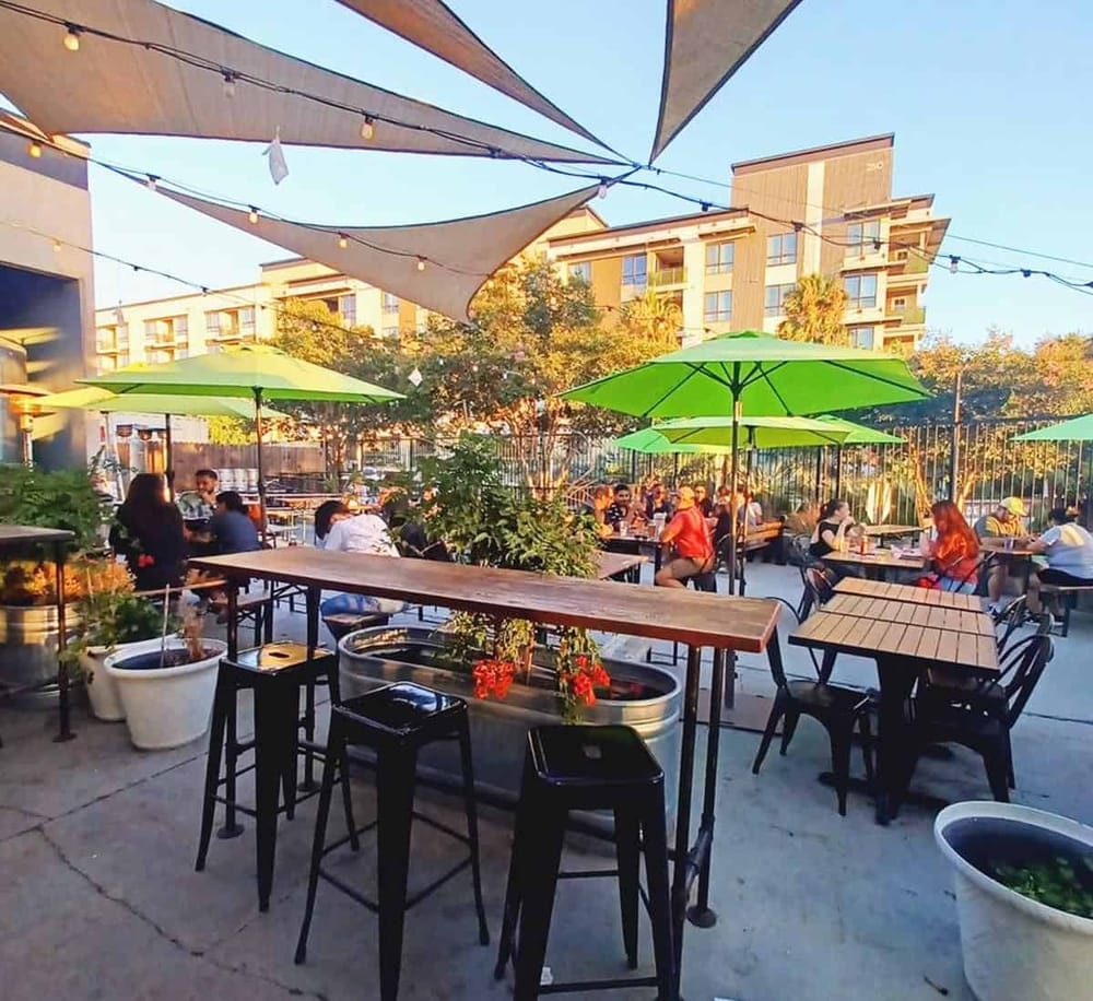 Outdoor dining area with green umbrellas and string lights at QuestForDirections restaurant.