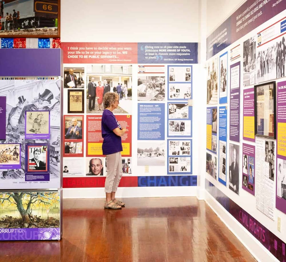 Reflective woman viewing historical exhibit on civil rights and political change at QuestForDirections museum.
