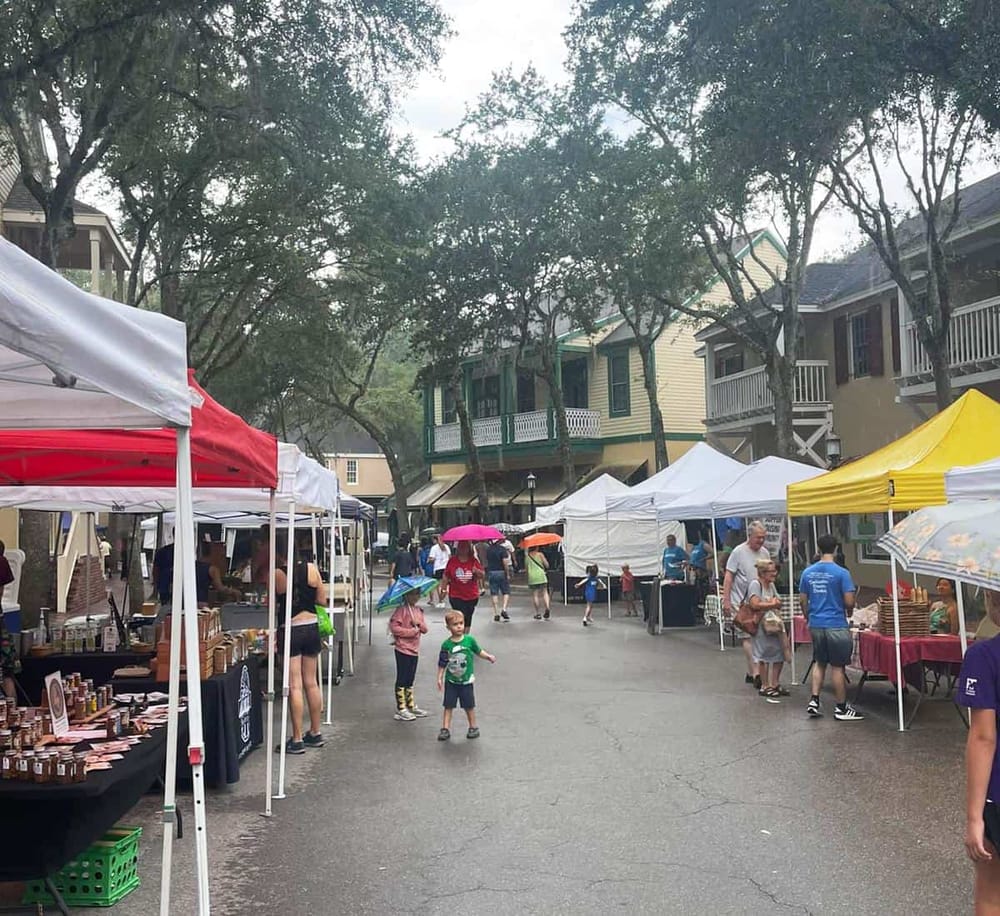 Colorful outdoor market with tents, people shopping, and vibrant atmosphere in a quaint neighborhood.
