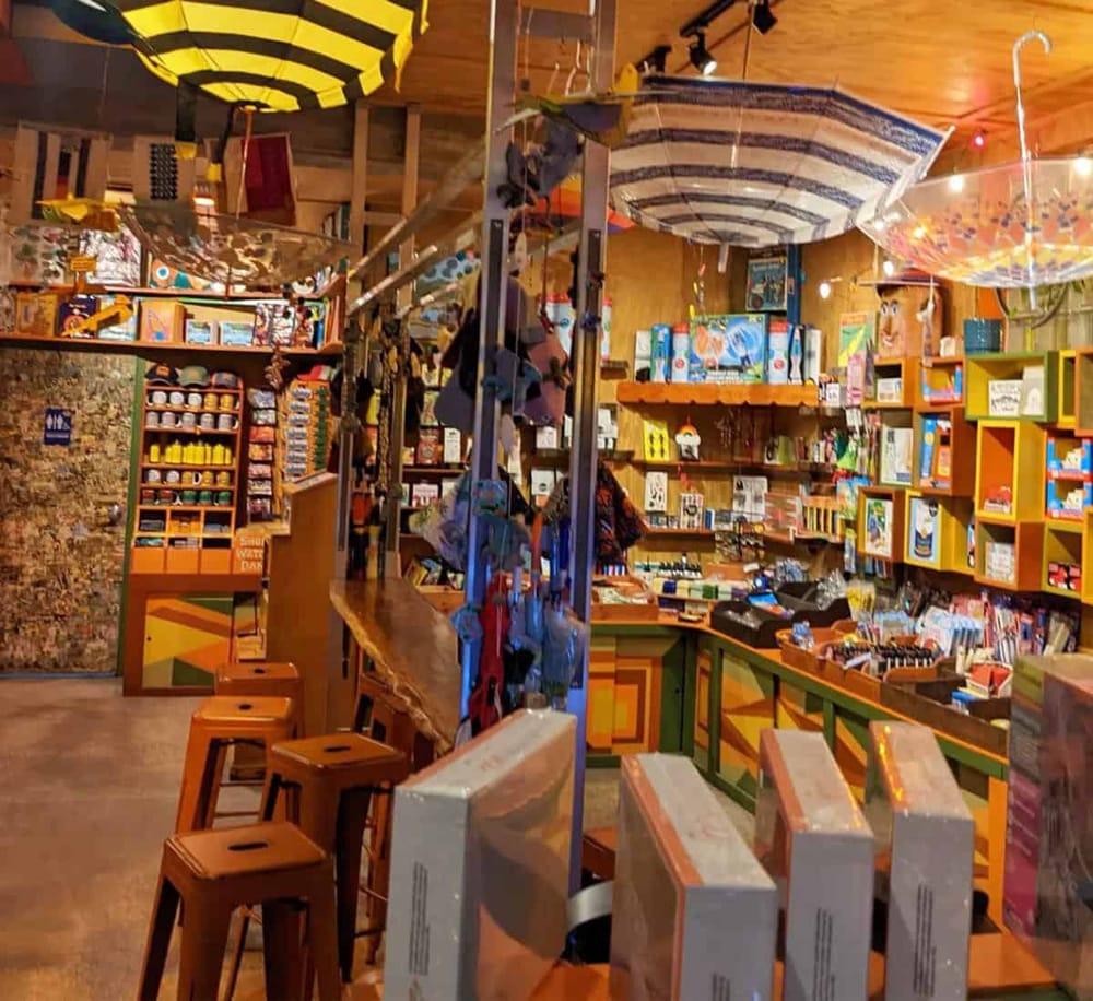 Colorful indoor toy store with vibrant shelves and playful umbrellas overhead.