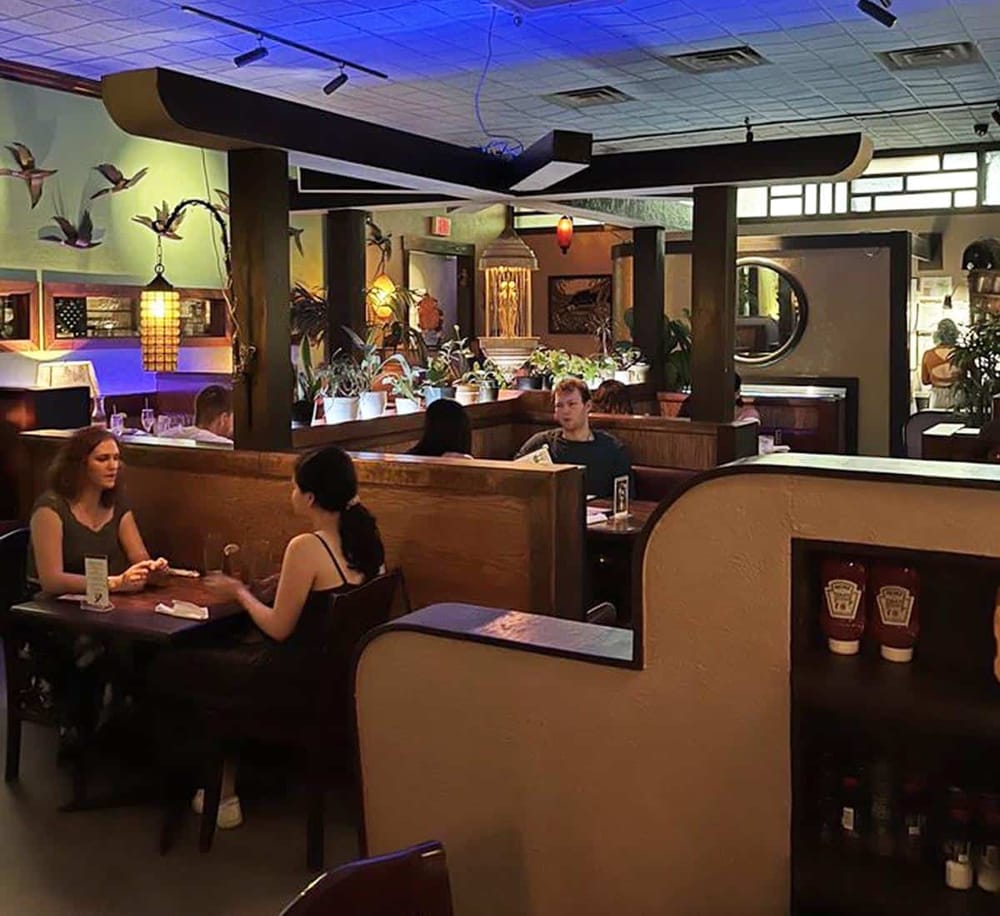 Cozy restaurant interior with booths, plants, and artistic decor for a relaxing dining experience.