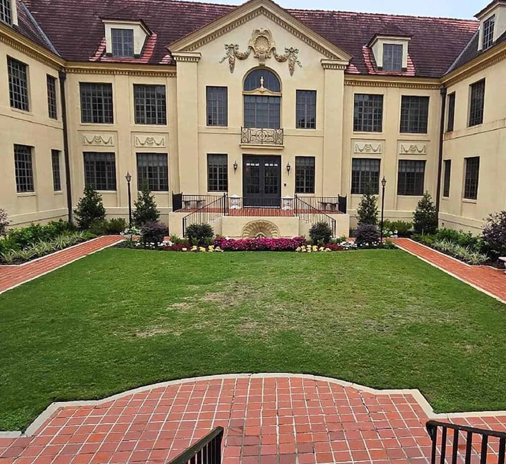 Elegant historical mansion with manicured front yard, vibrant flowerbeds, and classic architectural details for luxury event venues.