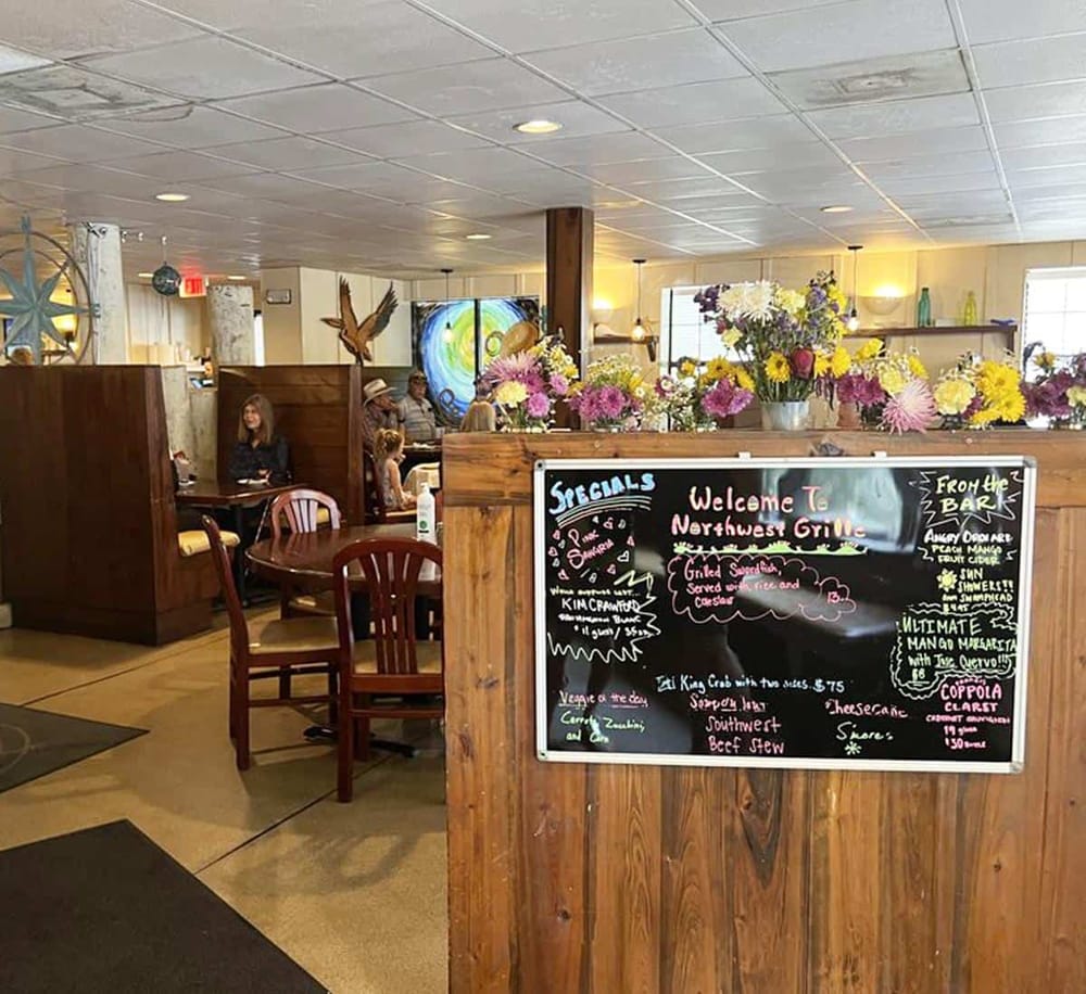 Cozy Northwest Grill restaurant interior with colorful floral decor and chalkboard menu. Suitable for dining and leisure.