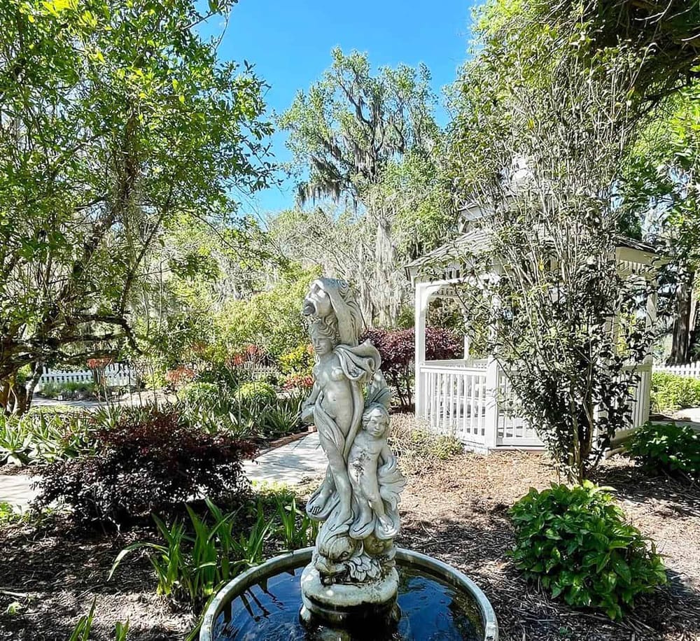 Serene garden featuring a classic sculpture fountain, lush greenery, and charming gazebo, perfect for outdoor relaxation.