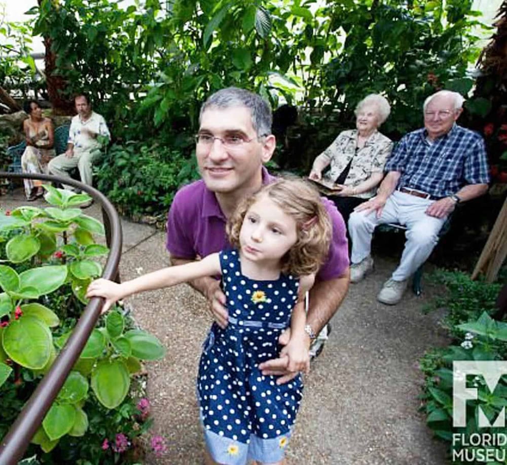 Colorful botanical garden with a diverse group of people enjoying a leisurely visit at the Florida Museum.