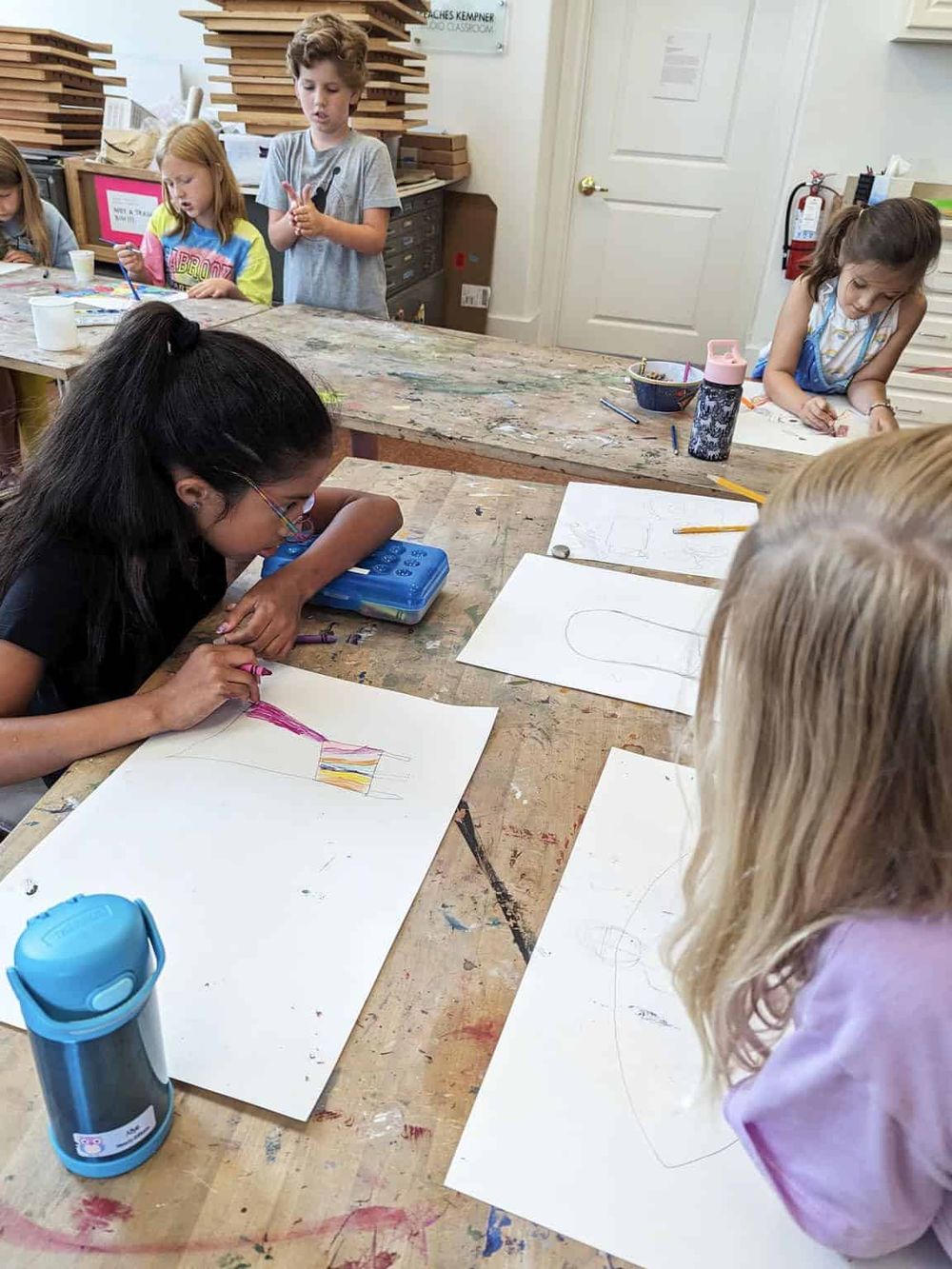 Kids creating colorful artwork in an art classroom, showcasing creativity and artistic skills.