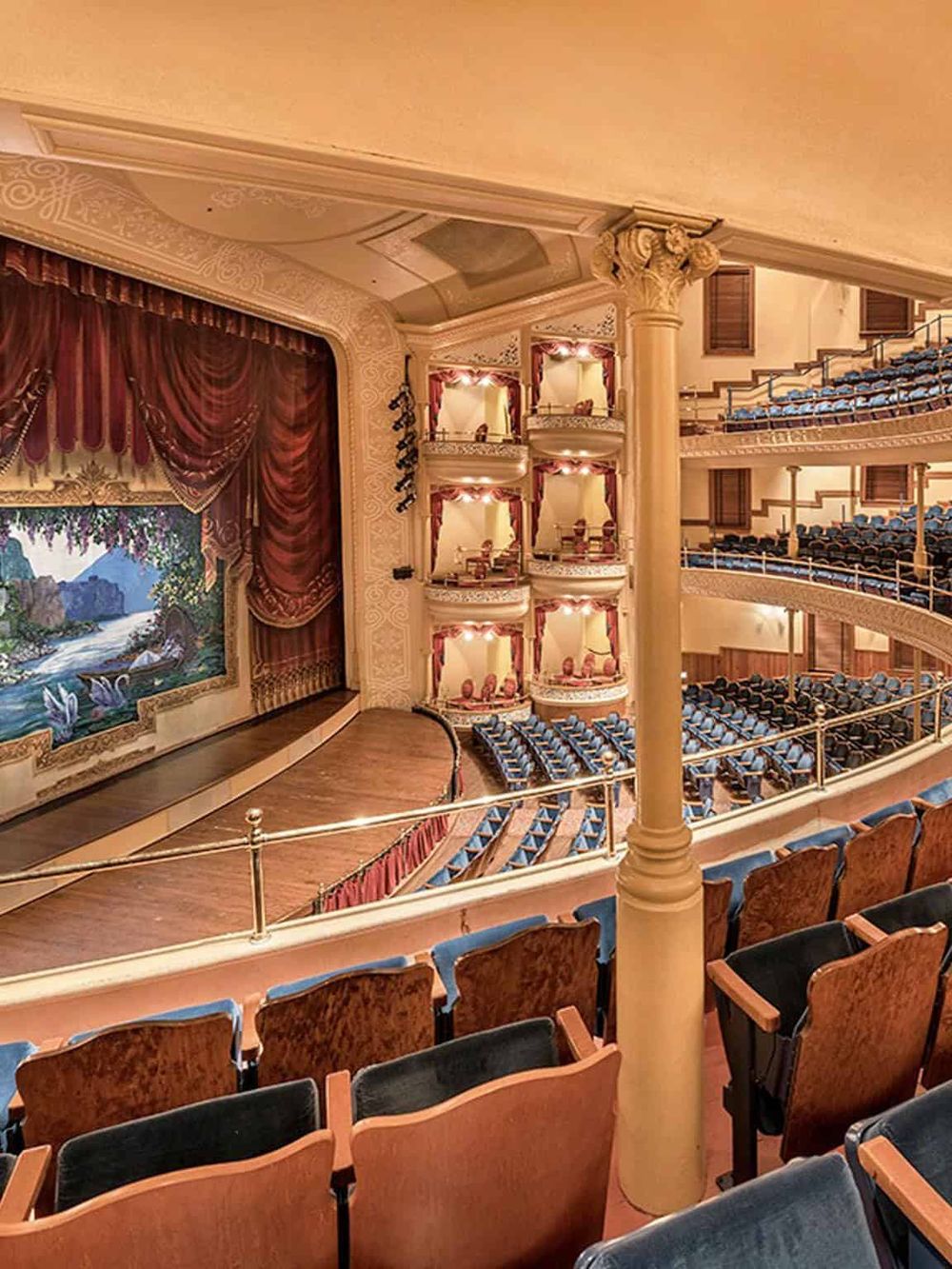 Elegant theater interior showcasing classic stage with ornate details and designated seating for performances.