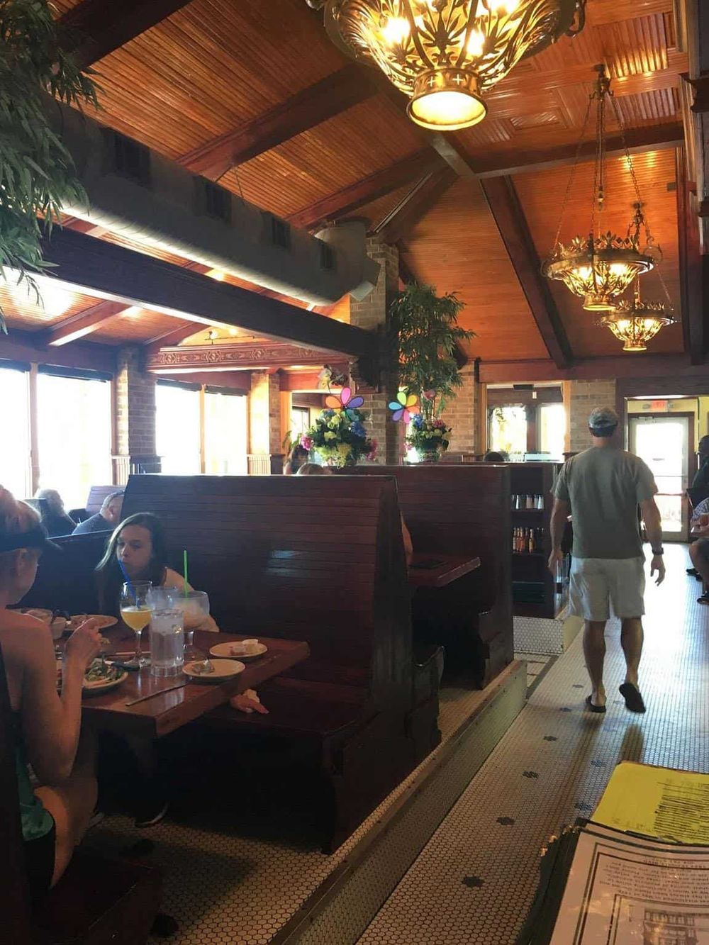 Cozy restaurant interior with wooden ceiling, ambient lighting, and diners enjoying meals.