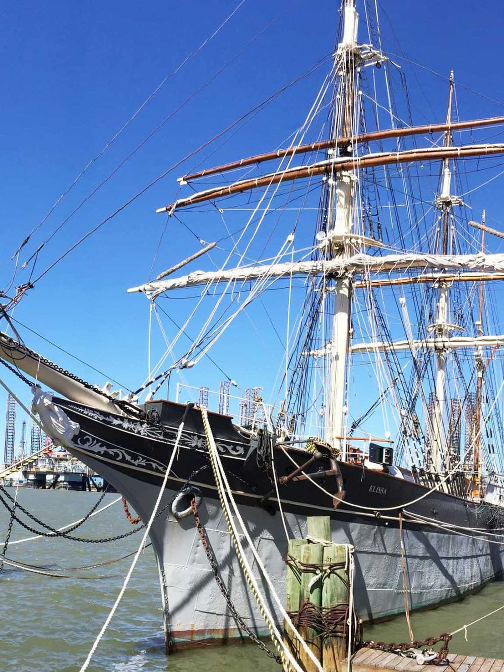 Majestic sailing ship docked at harbor with clear blue sky background.
