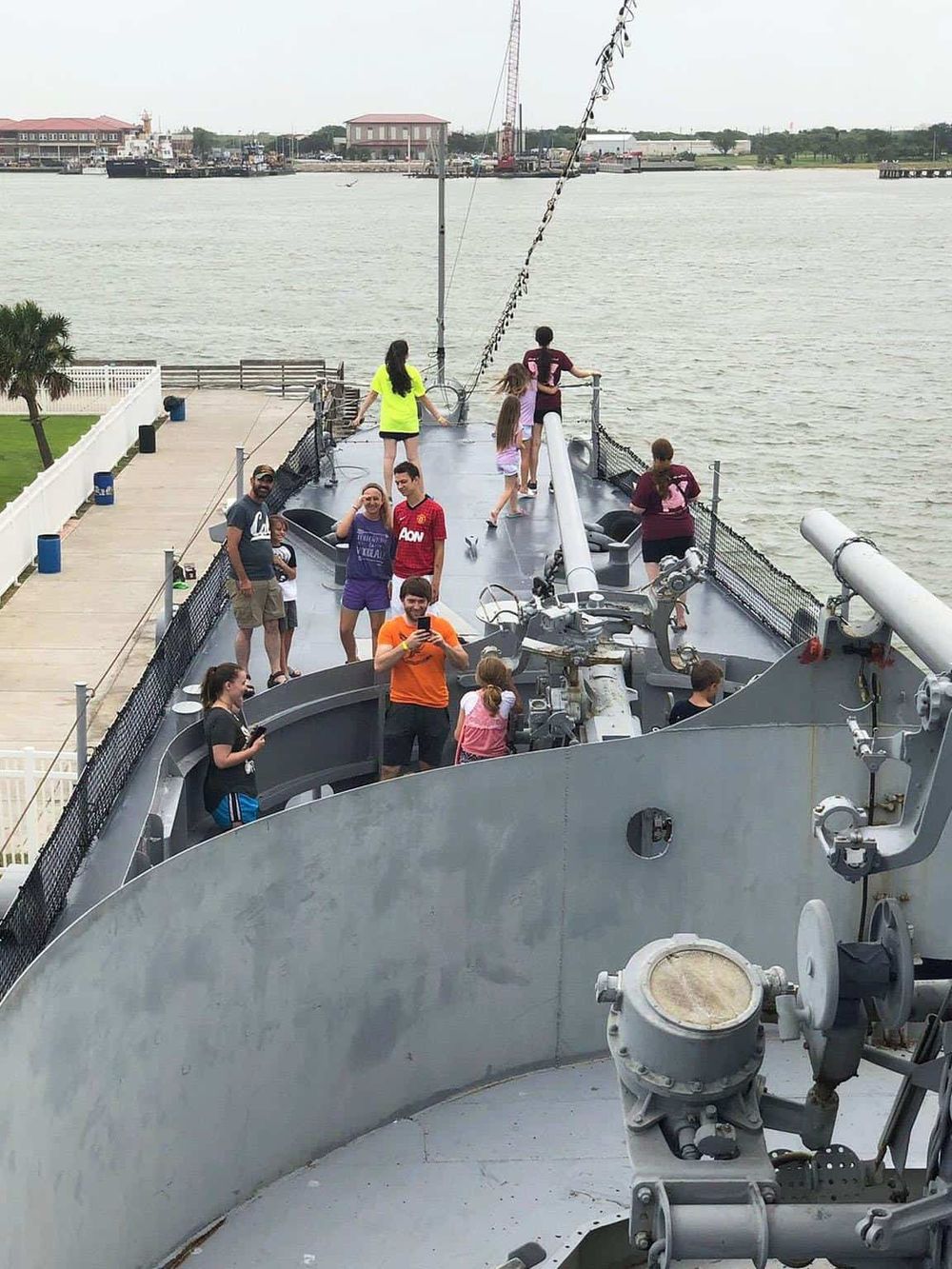 People on a battleship tour enjoying waterfront views and historical maritime experience.