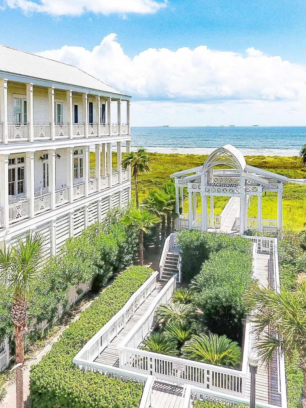 Beachfront resort with white balconies and lush tropical gardens by the ocean, perfect for beach vacations.