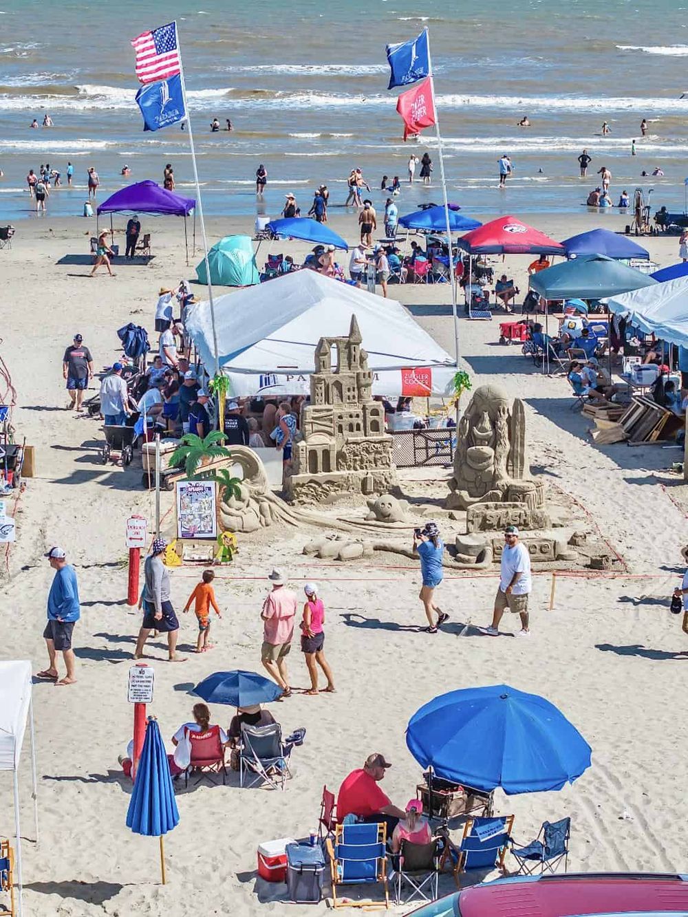 Sandcastle competition at the beach with umbrellas and shoreline activities, a perfect family-friendly summer destination.