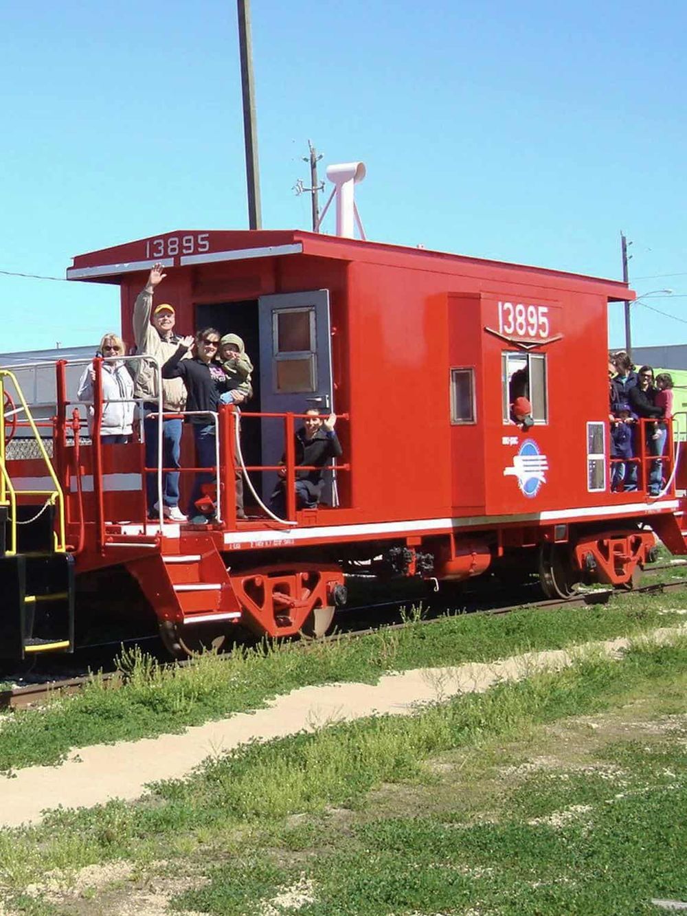 Red vintage railcar with people enjoying a scenic train ride for travel adventures.