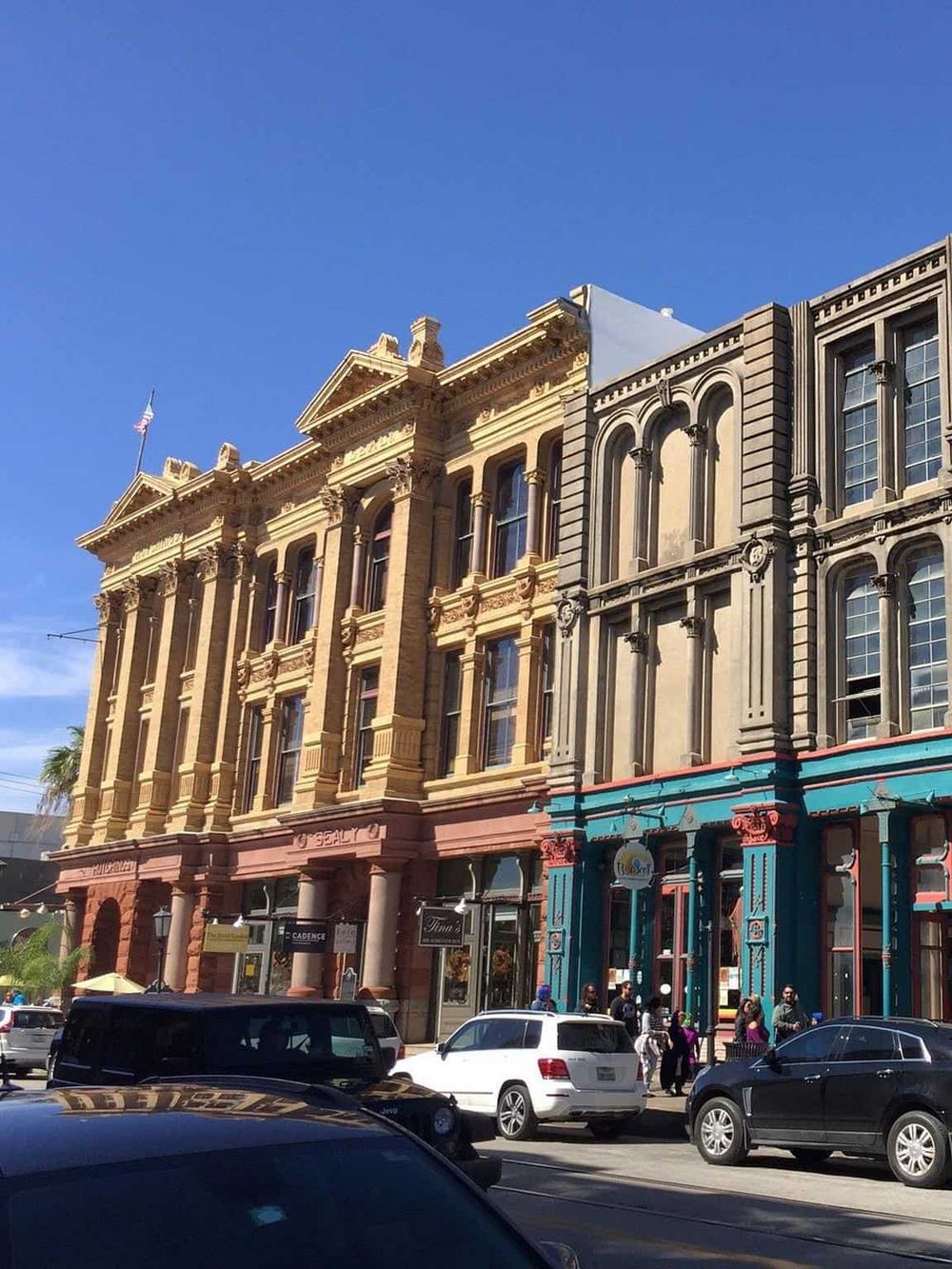 Colorful historic buildings on a lively city street with parked cars and pedestrians, representing urban exploration and local business districts.