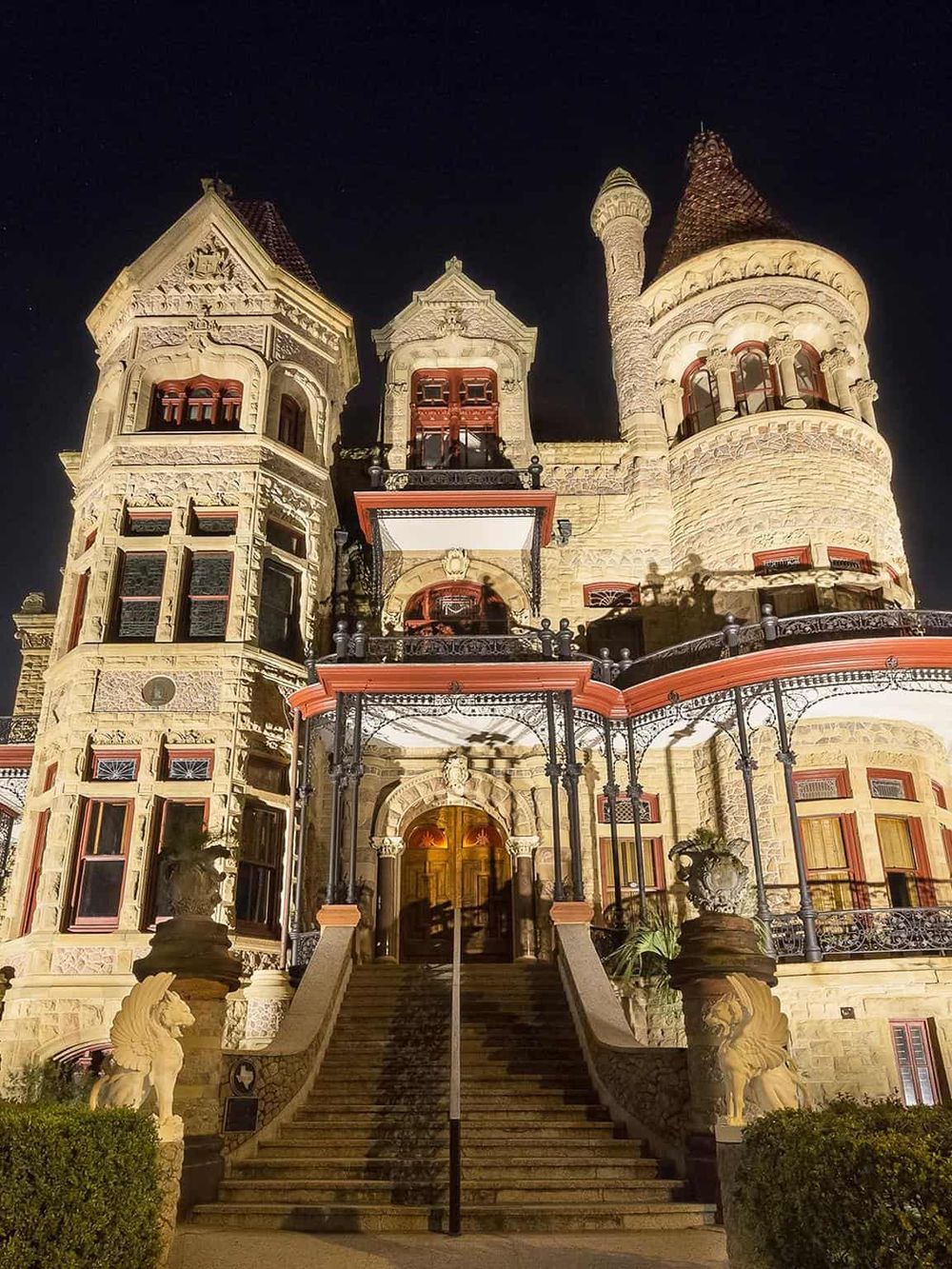 Intriguing castle-like mansion illuminated at night, showcasing elaborate architecture and ornate detailing.