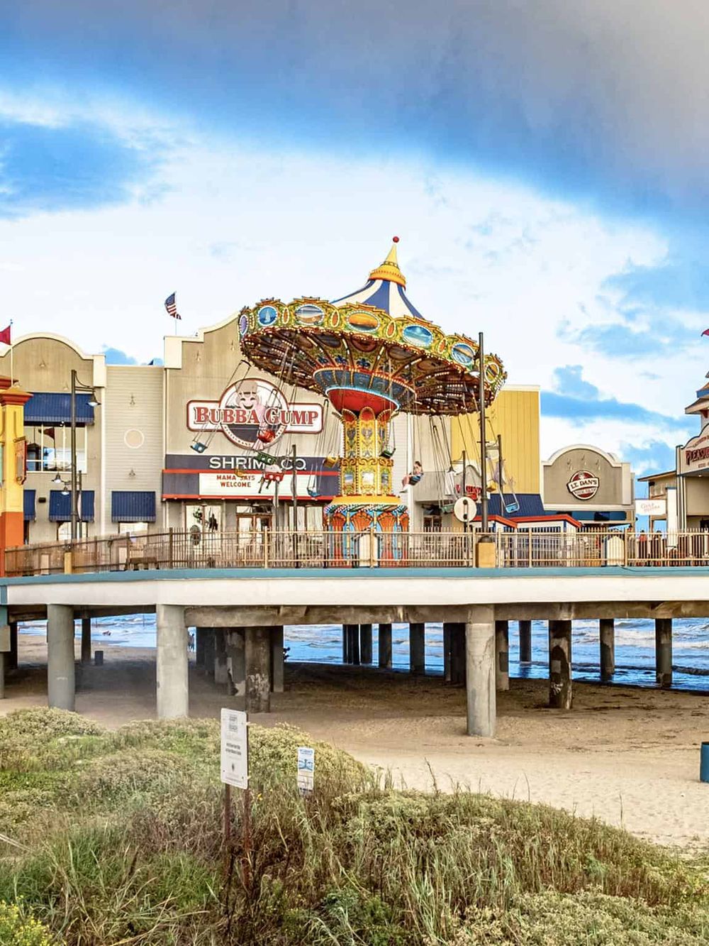 Amusement park swings carousel at the beach with colorful buildings, seaside, and blue sky.