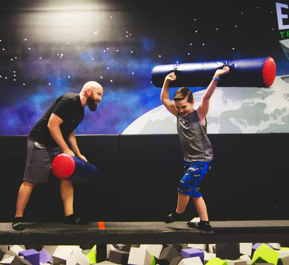 Energetic indoor foam pit with kids playing trampoline battle game at Quest for Directions.