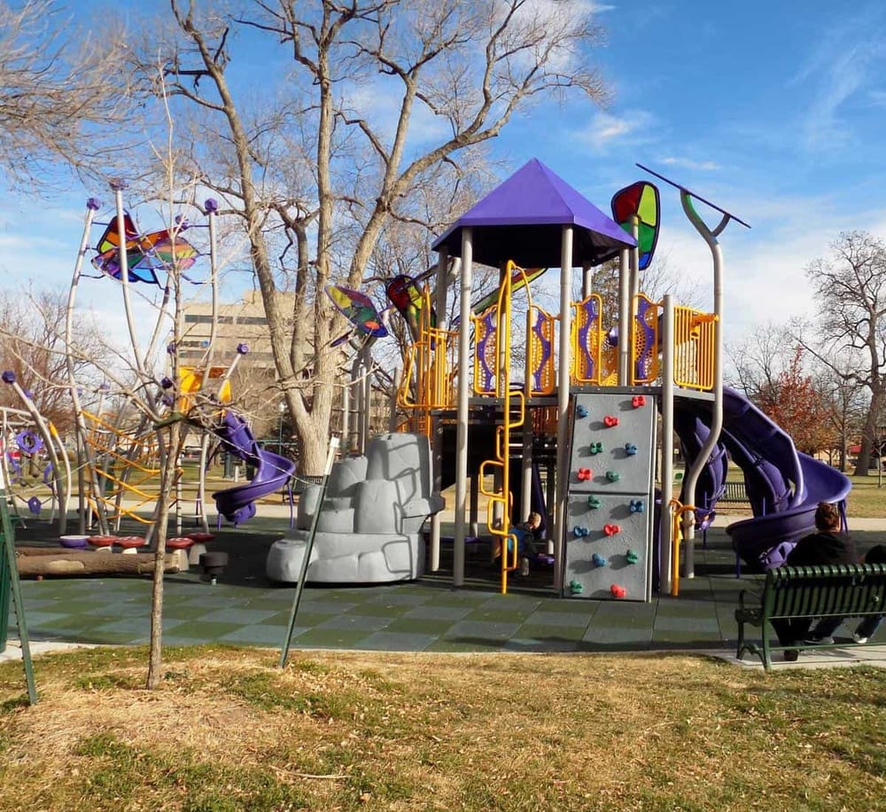 Colorful kids playground with slides, climbing wall, and interactive elements at a park. Perfect for family fun and outdoor recreation.