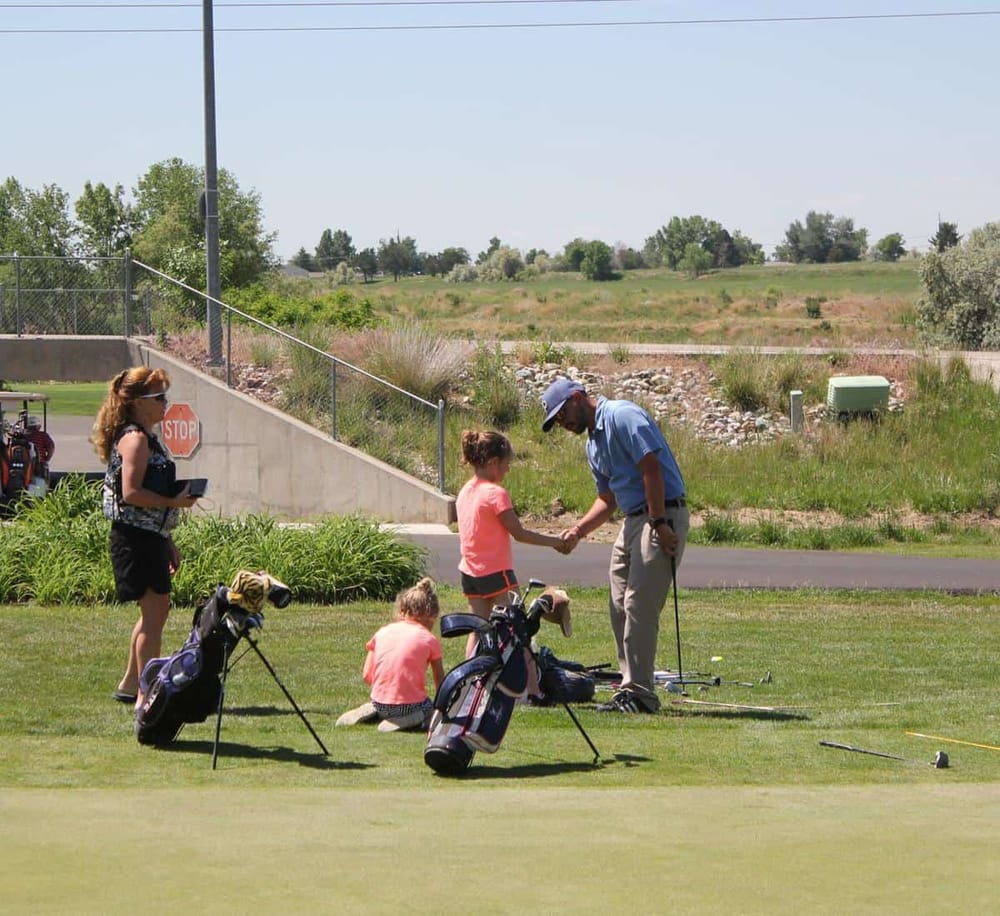 1. People playing golf on a sunny course with golf bags and a golf cart visible.