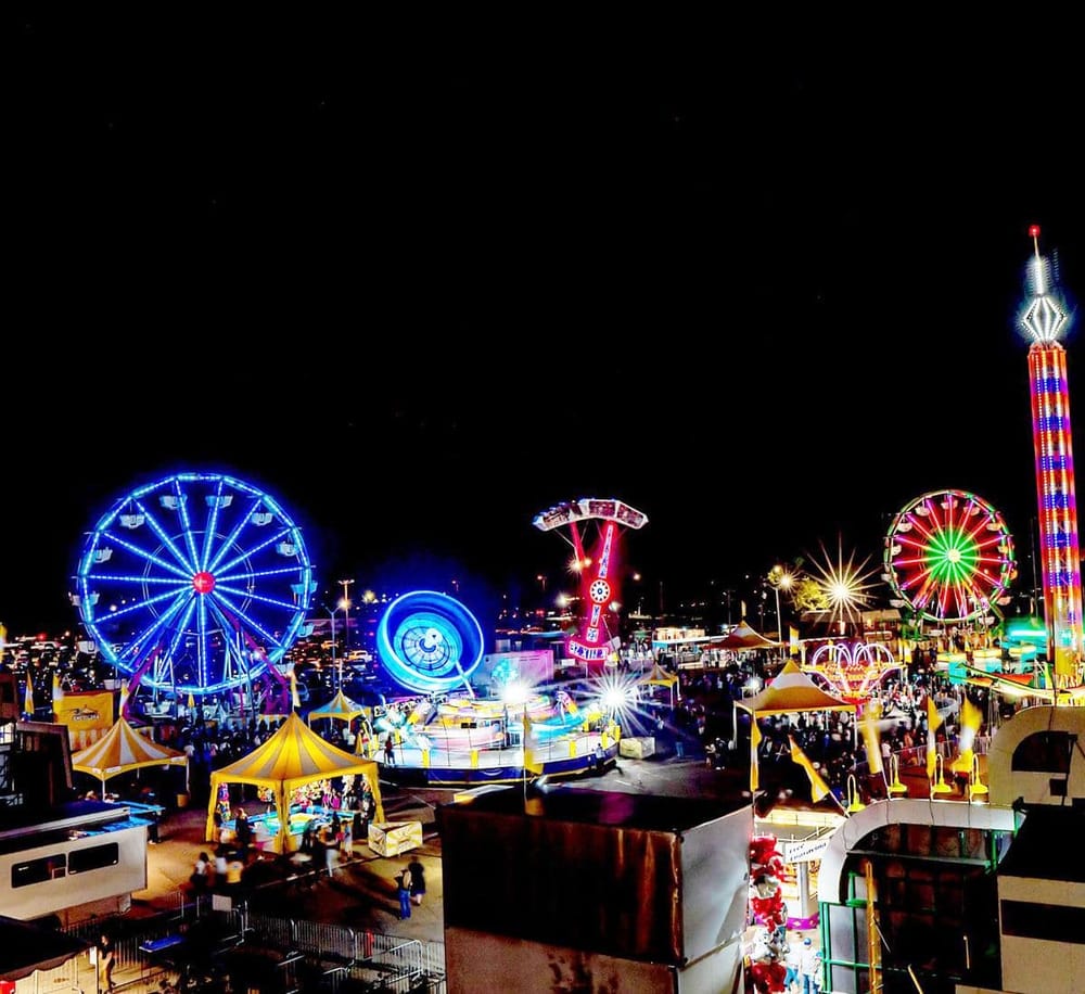 Colorful amusement park rides at night illuminated with vibrant LED lights, creating a lively carnival atmosphere.