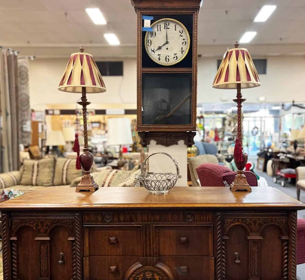 Antique wooden clock with lamps in furniture store display, vintage home decor.