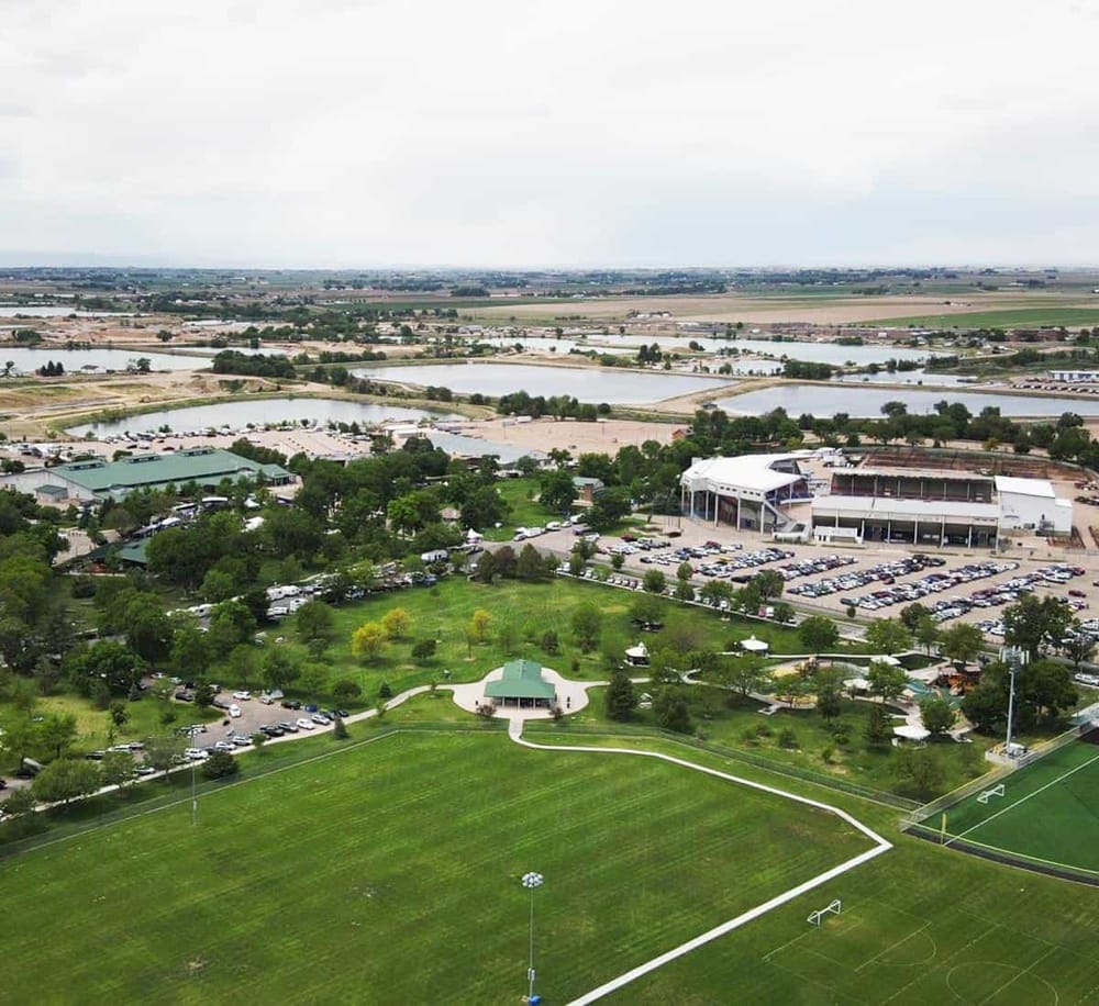 Aerial view of Quest For Directions sports complex with lush field, parking, and nearby water bodies.