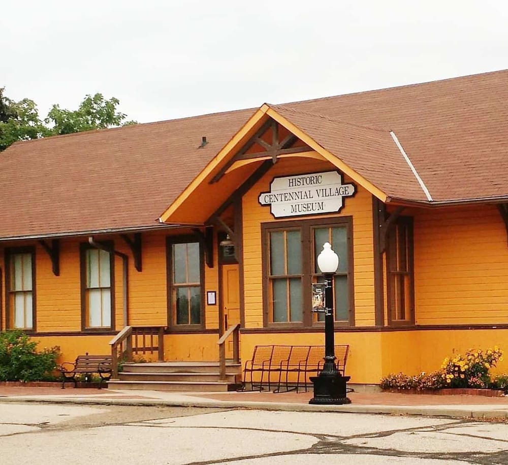 Colorful historic village museum building with wooden exterior, welcoming steps, and vintage lamp post.