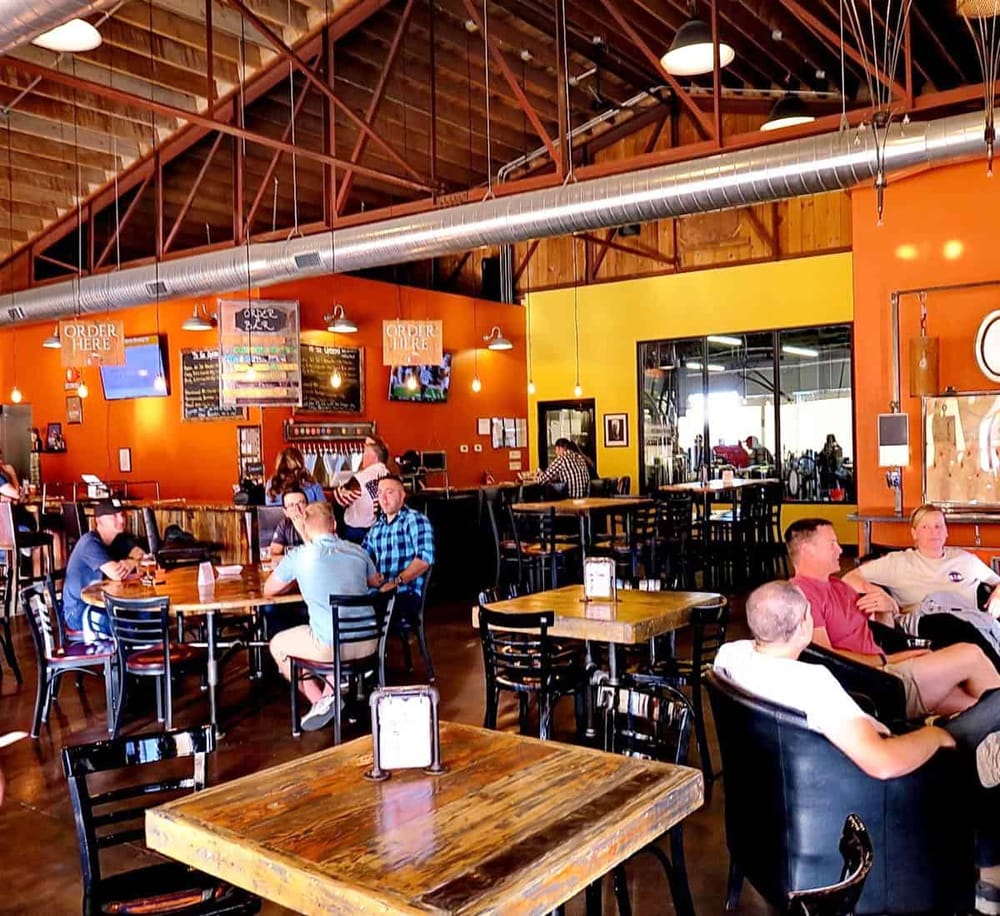 Cozy restaurant interior with wood beams, vibrant walls, and groups of people dining.