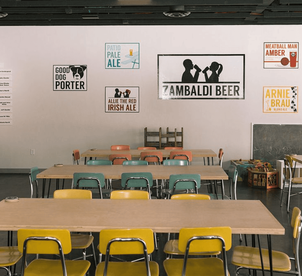Colorful beer-themed wall art in a modern taproom or brewery seating area.