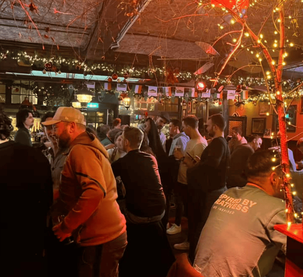 People enjoying nightlife at a festive bar with Christmas lights and decorations.