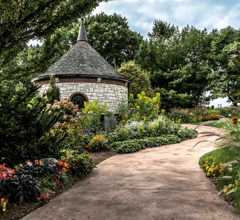 Charming garden with stone roundhouse and vibrant flower bed, perfect for outdoor relaxation and botanical exploration.