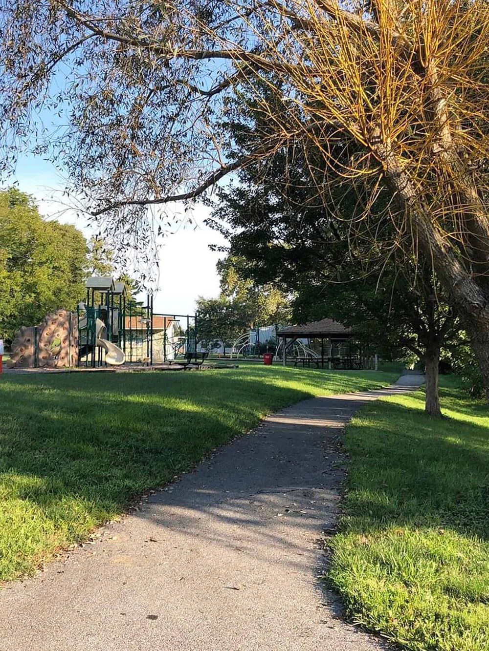 Playground and park area with walking path, greenery, trees, and outdoor leisure space.