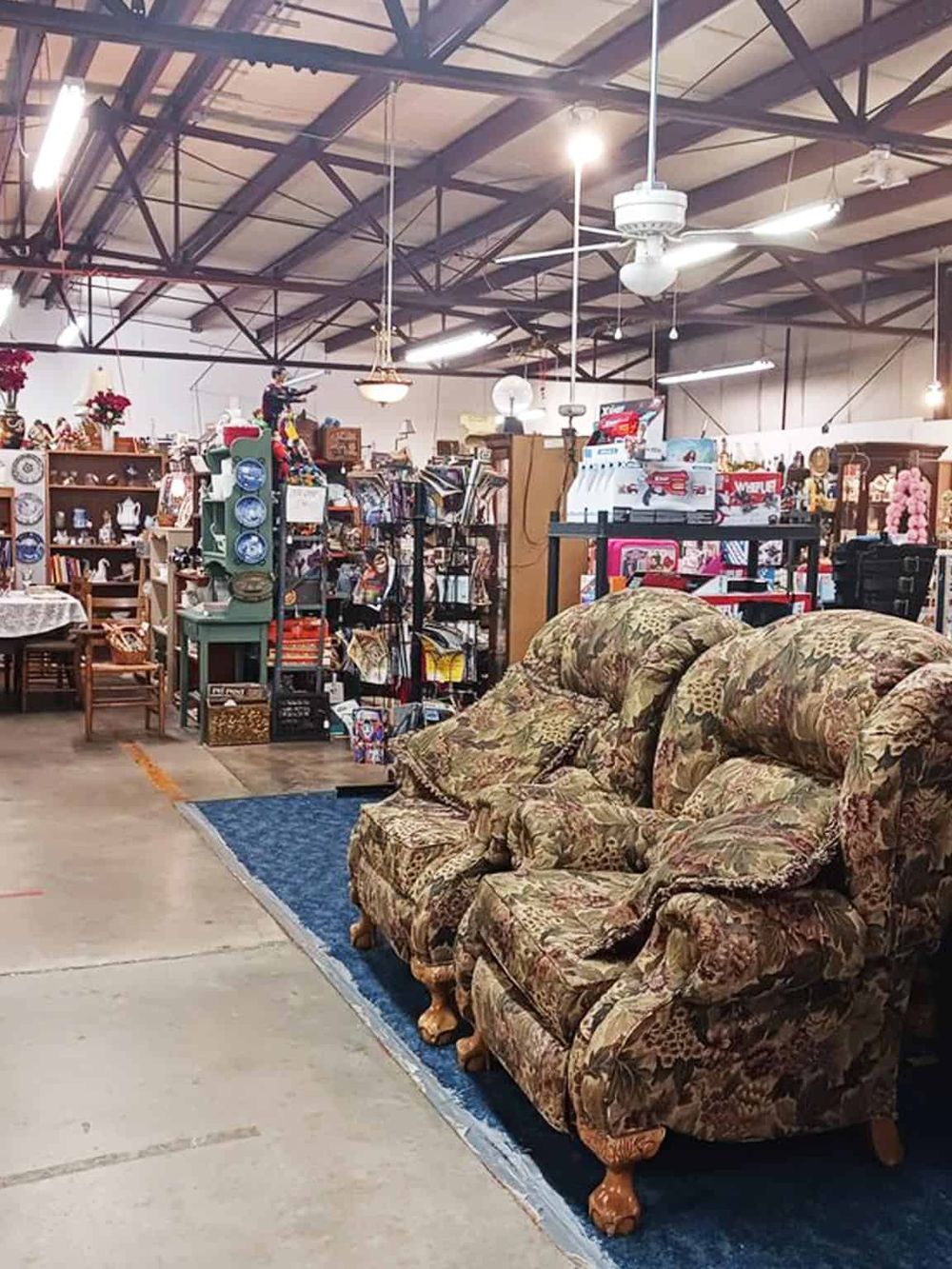 Vintage floral sofa in a thrift store with furniture, decor, and collectibles.