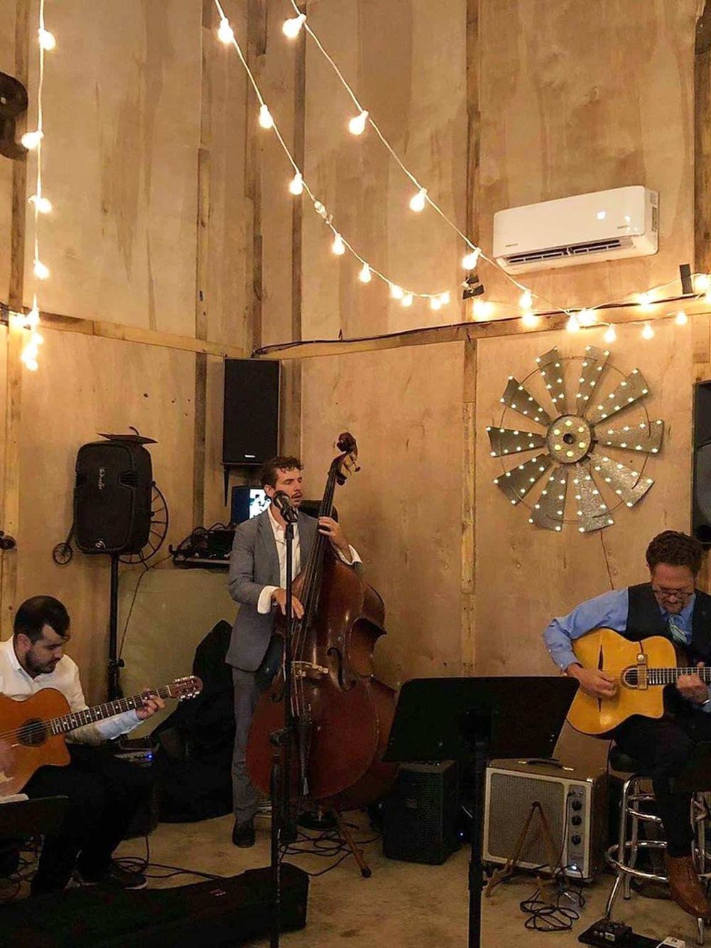 Live band playing jazz music at a cozy wooden venue with string lights and rustic decor for a memorable event.