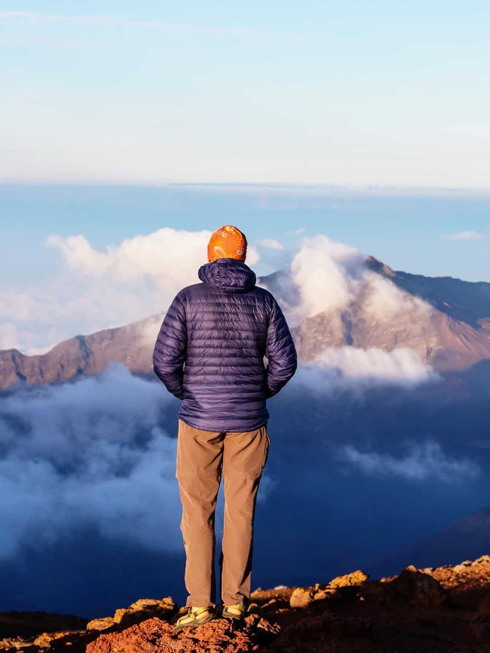 Stunning mountain view with hiker overlooking clouds and volcanic peaks, perfect for outdoor adventure seekers.