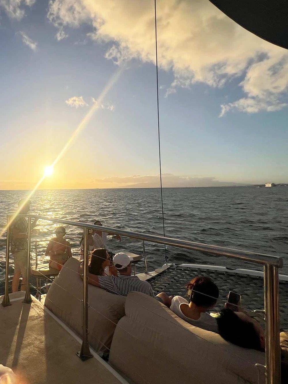 Sunset view on a boat with people relaxing and enjoying the ocean scenery, perfect for travel and leisure experiences.