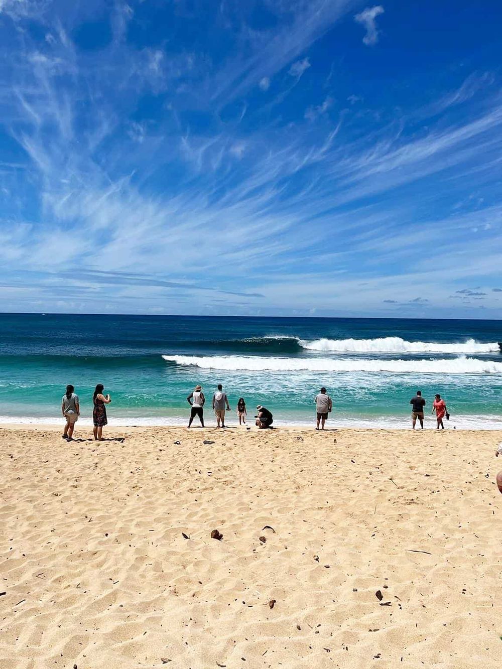 Stunning beach scene with ocean waves, blue sky, and people enjoying seaside view at QuestForDirections.