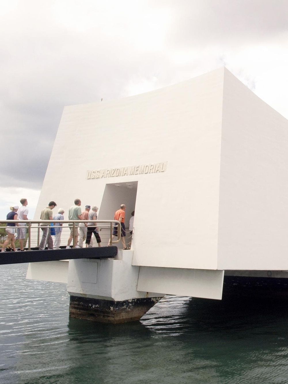 Modern USS Arizona Memorial at Pearl Harbor, visitors paying respects to fallen soldiers.