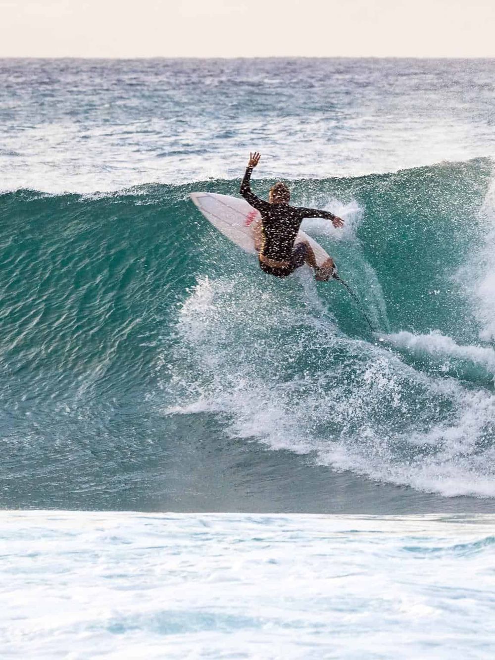 Vibrant surfer riding a wave at the beach with surfboard and water splash.