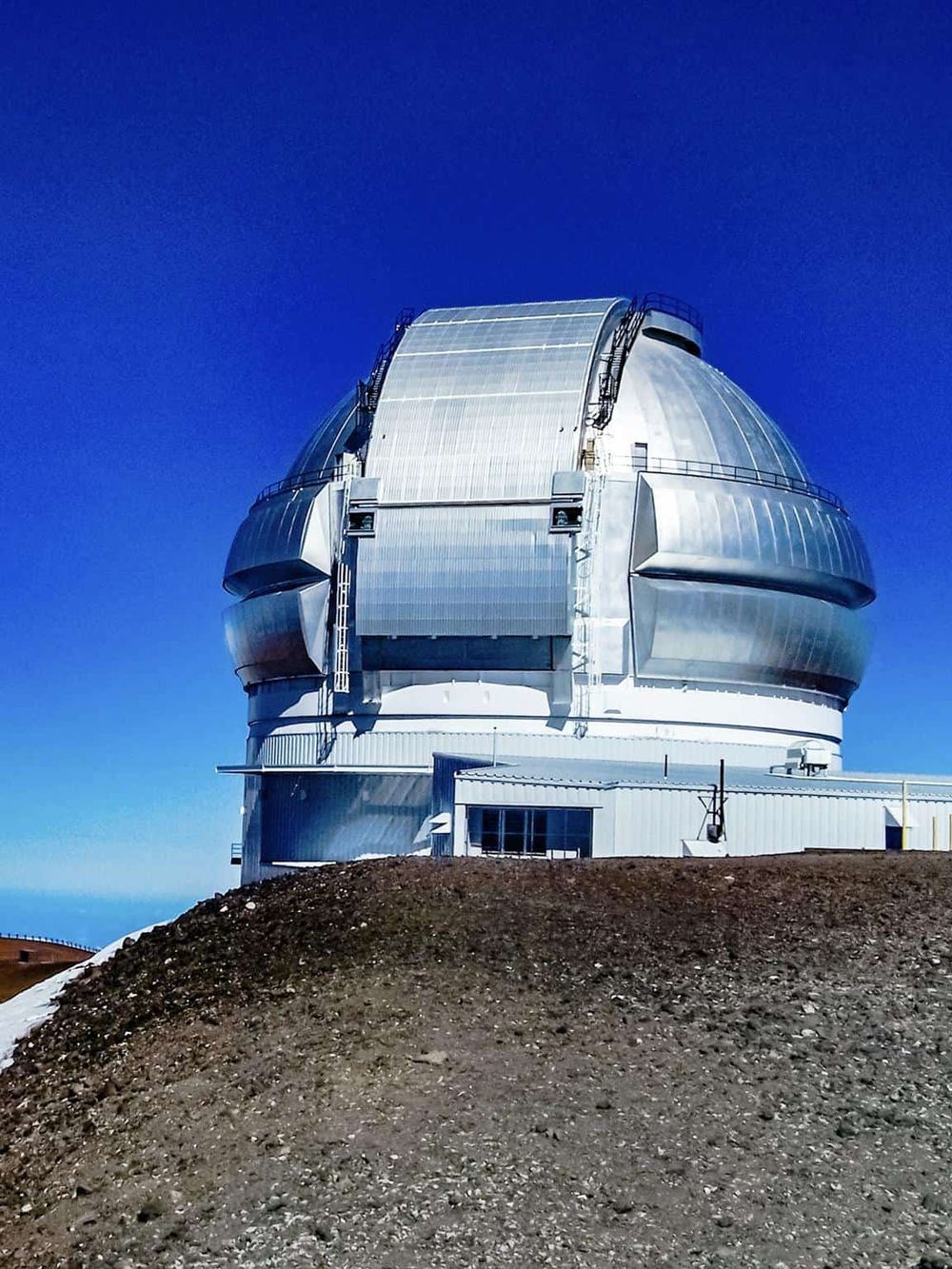 High-tech observatory dome on mountain with clear blue sky, innovative technology, and scenic landscape.