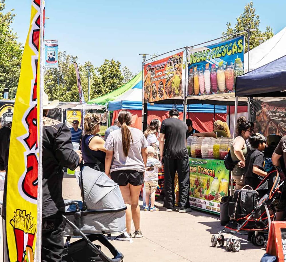 Colorful outdoor food festival with diverse vendors and visitors enjoying street food.