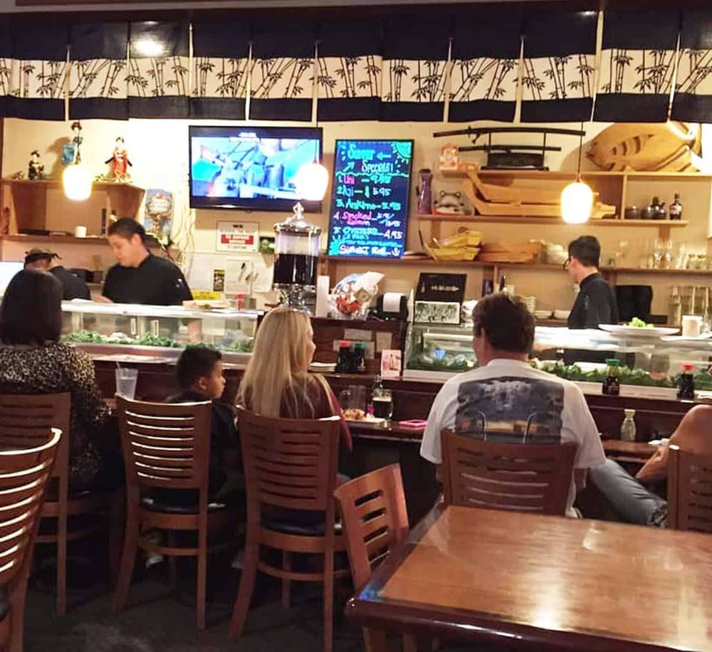 Enjoying sushi at a cozy Japanese restaurant with sushi bar and flat-screen TVs.