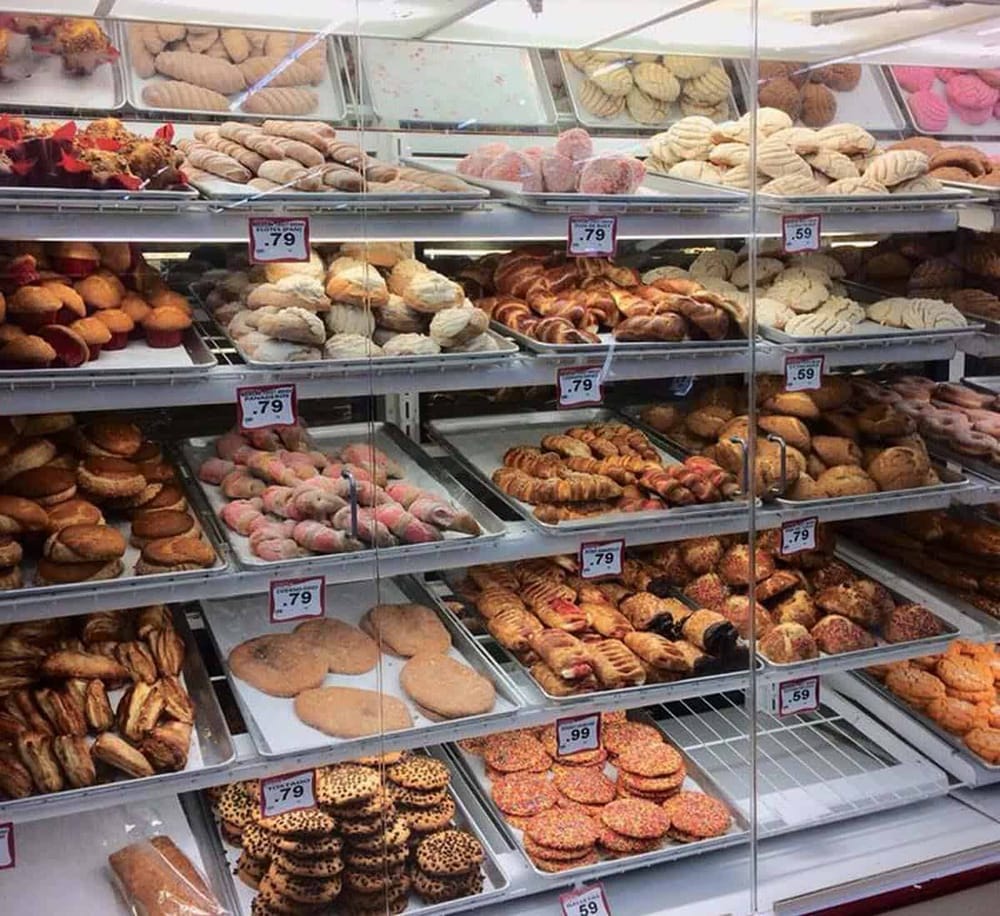 Fresh bakery cookies and pastries in a supermarket display case with price tags.