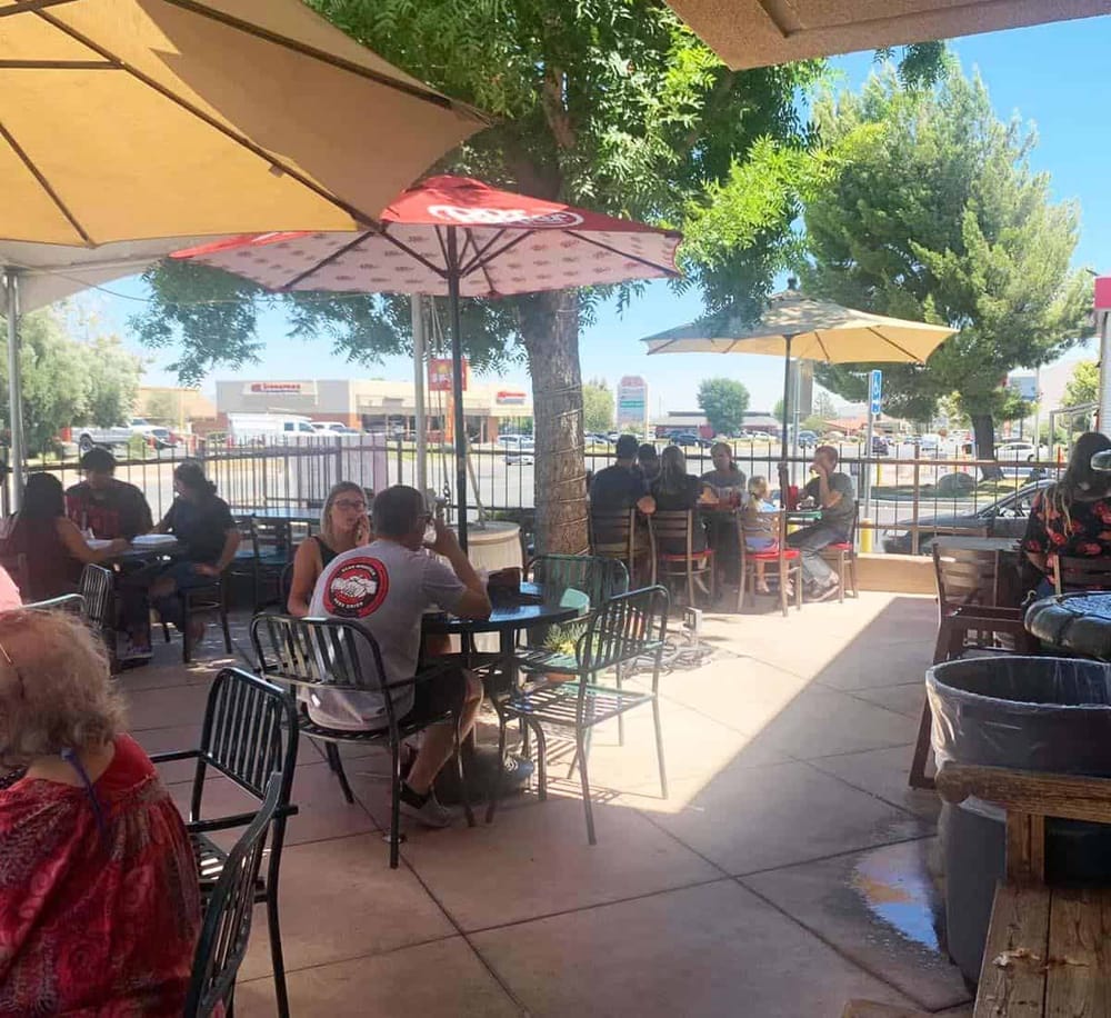 Outdoor dining area at QuestForDirections restaurant with umbrellas and people enjoying meals.