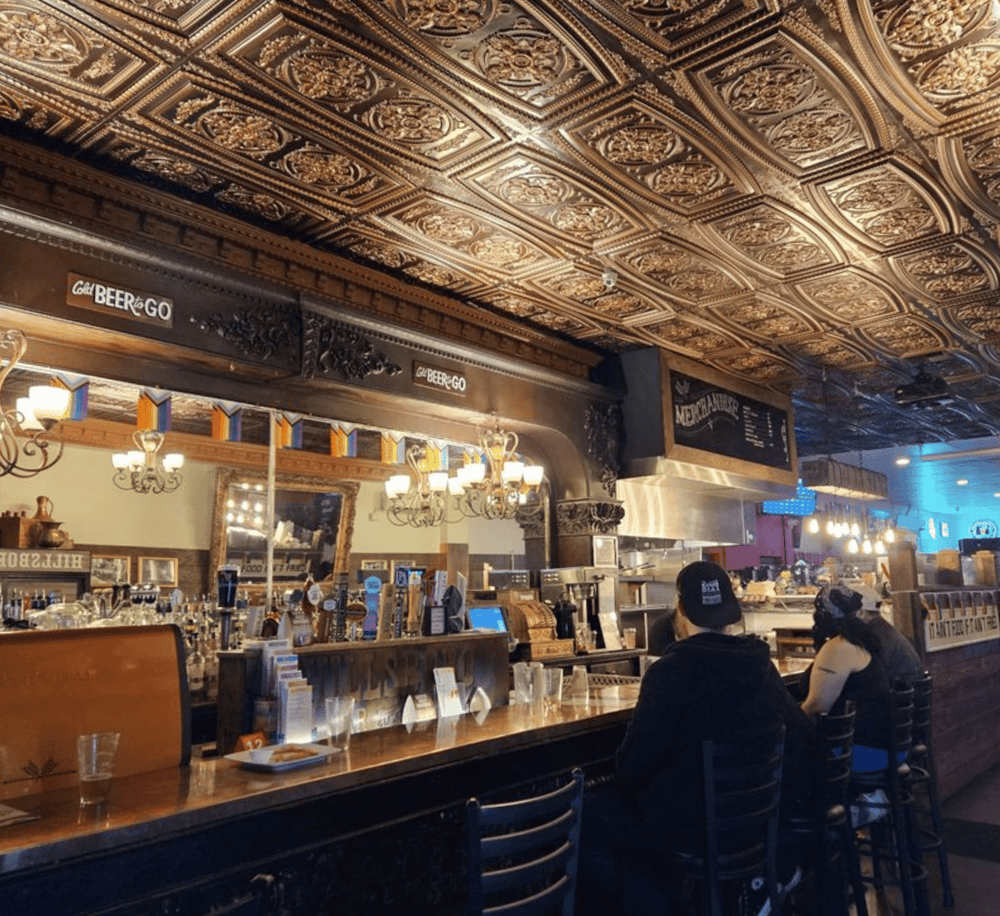 Cozy bar with ornate embossed tin ceiling and vintage decor, perfect for craft beer and socializing.