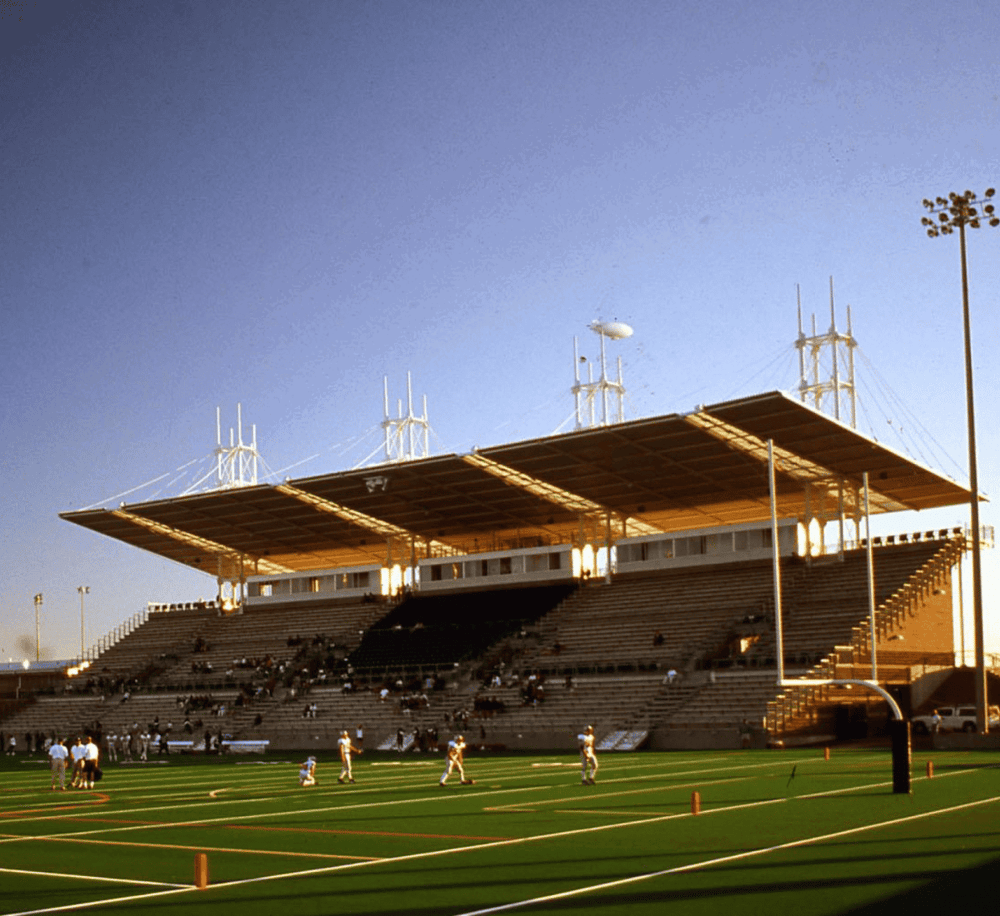 Stadium with modern architecture and football field during the day.