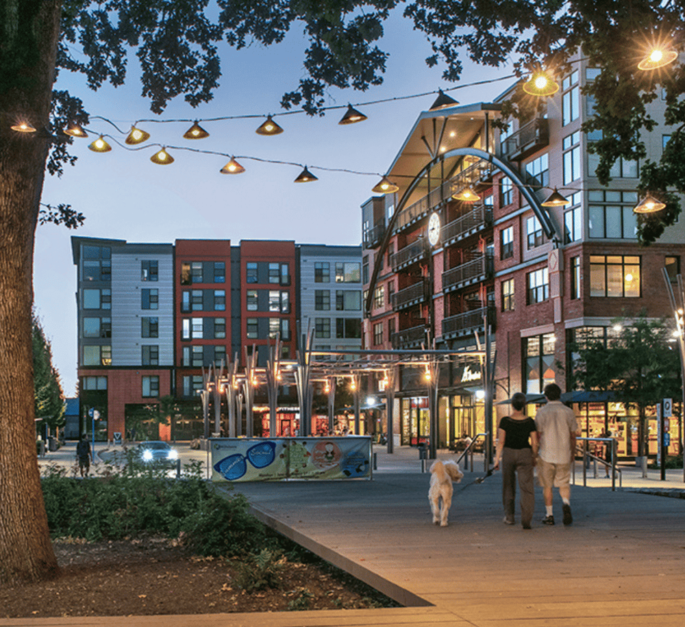 Vibrant downtown neighborhood with modern apartments and outdoor evening lighting, perfect for urban living and social outings.