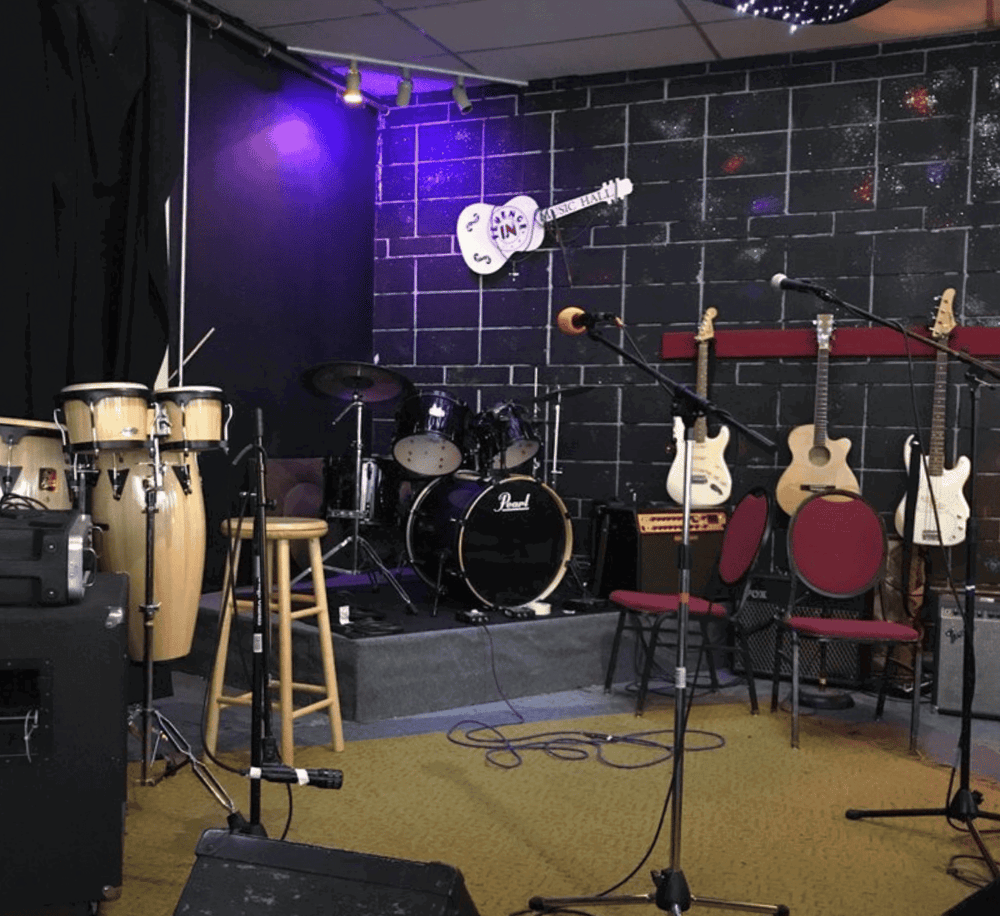 Colorful music stage setup with drums and guitars in a cozy venue. Ideal for live performances and musical events.